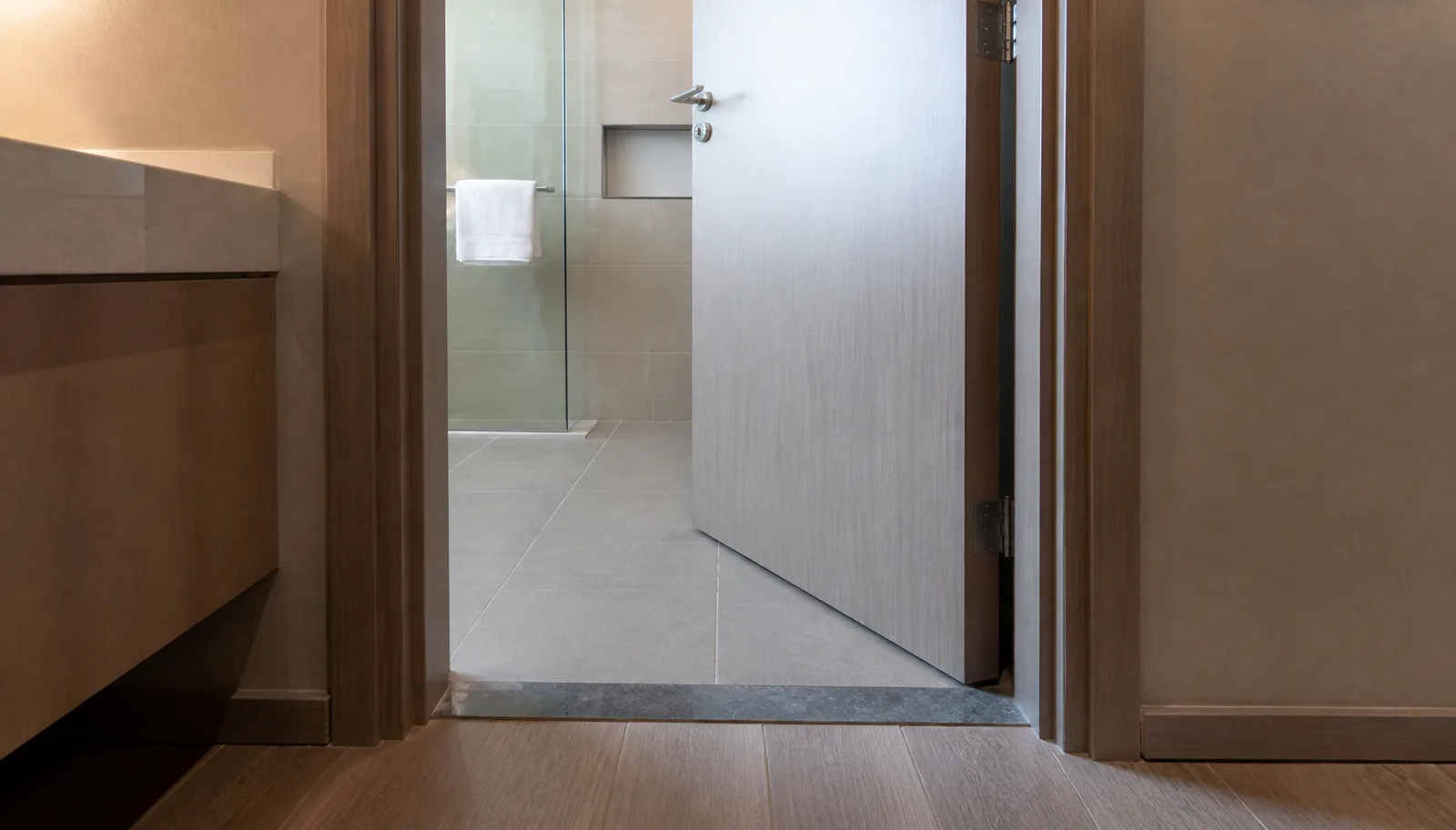 WPC bathroom door with stainless hardware at a tiled wet-area entrance