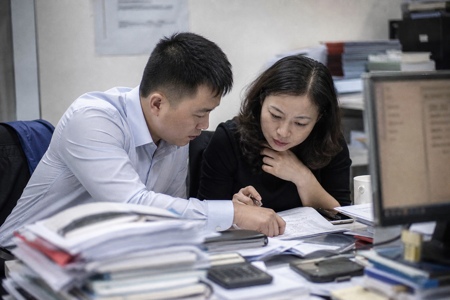 Chinese engineer and procurement manager reviewing a door schedule RFQ at a project desk