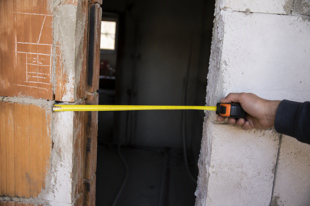 Contractor measuring a residential rebuild door opening with a tape measure